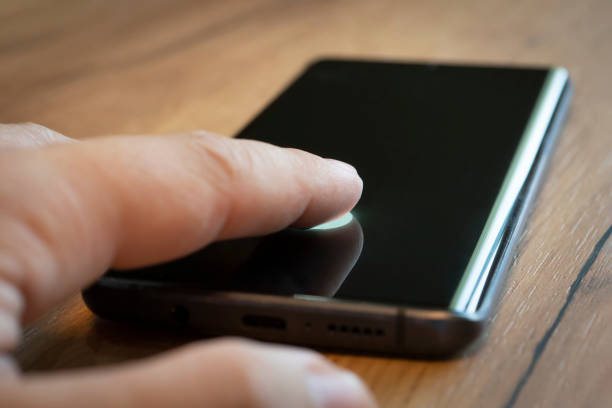 istock Biometric Identification. Unlocking Smartphone Scanning Fingerprint With Personal Verification App. male finger presses on the smartphone screen to unlock by fingerprint. 1461414240