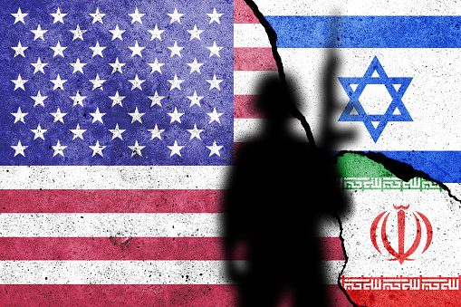 Flags of United States of America, Israel and Iran painted on the concrete wall with soldier shadow.