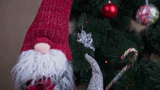 New Year's Scandinavian Gnome Stands Near the Christmas Tree