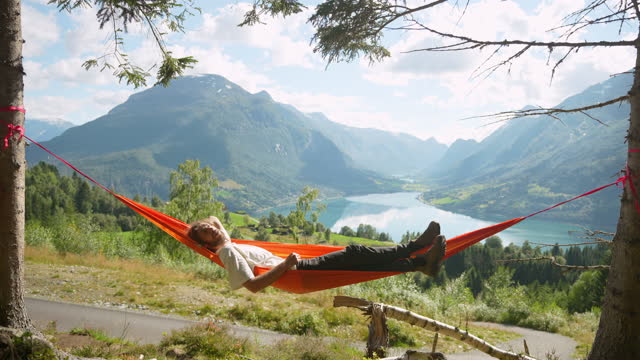 Man resting in hammock on the background of the lake