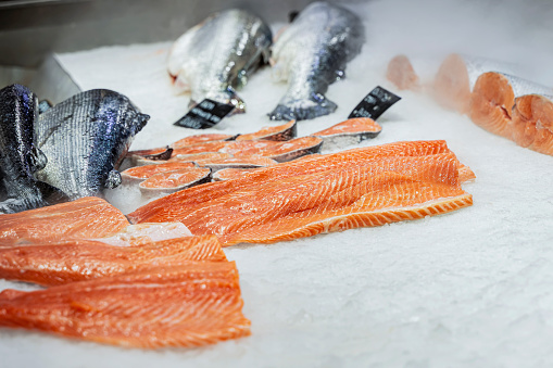 Sliced salmon, steaks, fish pieces lying on ice in grocery store
