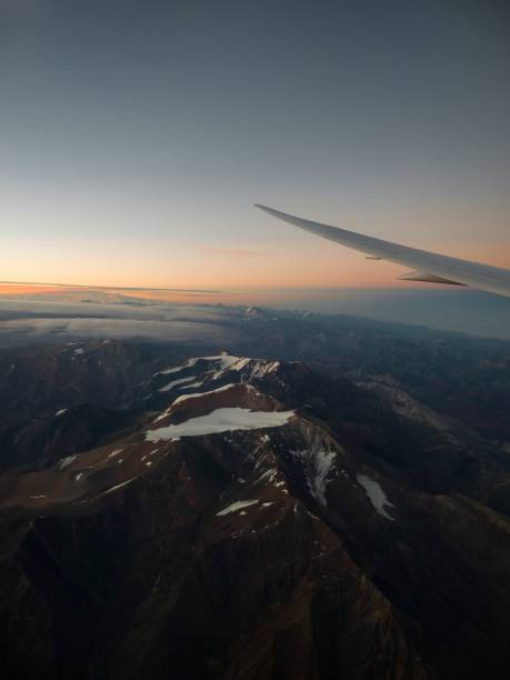 サンティアゴデチリの飛行機の窓側の座席から飛行機の翼を持つ雪をかぶったアンデス山脈の夕日のパノラマビュー - mountain range earth sky airplane ストックフォトと画像