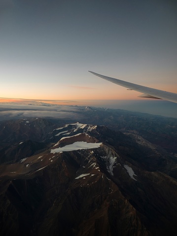 Panorama view of sunset in snowcapped andes mountains with aeroplane wing from airplane window seat landing in Santiago de Chile South America