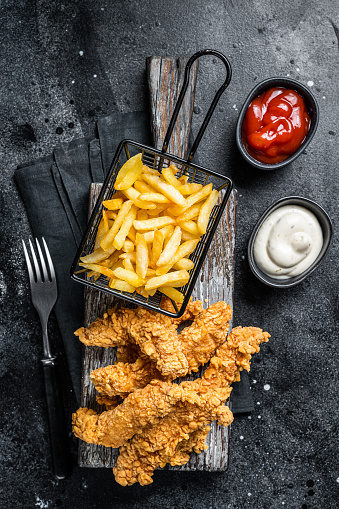 Chicken breast strips with French Fries and Ketchup. Black background. Top view.