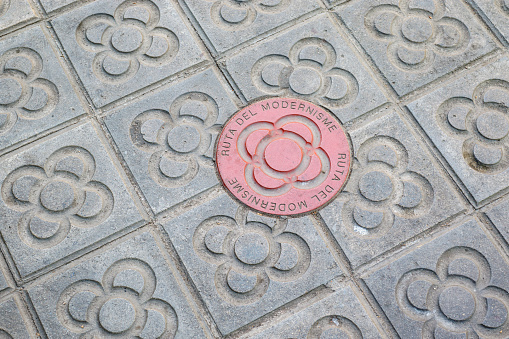 Sidewalk with panot (tiles with flower inside) and the red Ruta Modernista panot in Barcelona, Catalonia, Spain, Europe