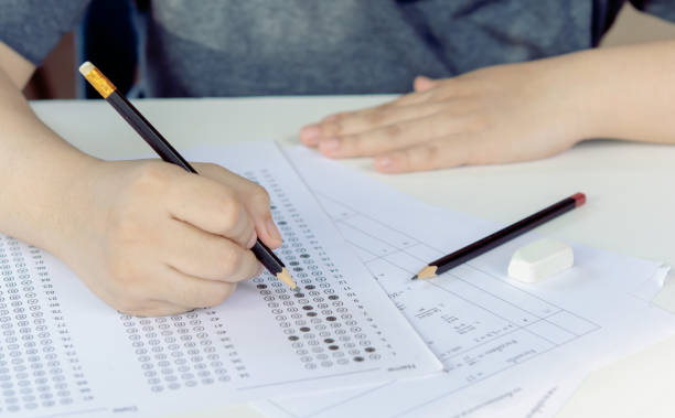 istock Students hand holding pencil writing selected choice on answer sheets and Mathematics question sheets. students testing doing examination. school exam 1461421256
