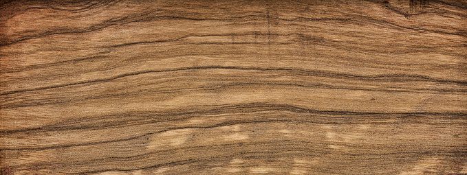 The wood is red and brown color with layers and lines like a rose petal. High angle view of a flat textured wooden board backgrounds. It has a beautiful nature and abstractive pattern. A close-up studio shooting shows details and lots of wood grain on the wood table. The piece of wood at the surface of the table also appears rich wooden material on it, shows elegant and soft textured. Flat lay style.