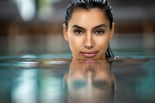 Portrait of beautiful woman relaxing and enjoying in swimming pool at morning. Photo taken under available light
