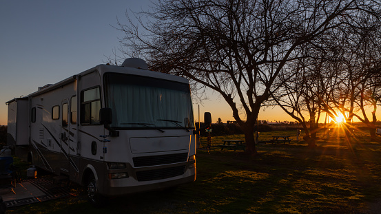 Sunsets on motorhomes at campsites under blue sky and trees