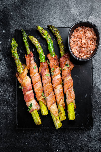 istock Asparagus Baked with bacon and spices. Black background. Top view 1461423729