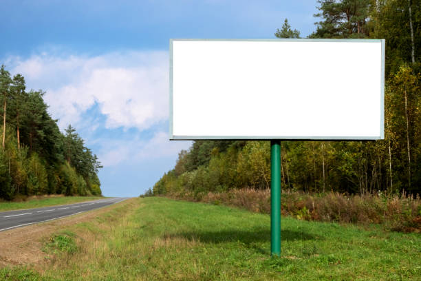 Big empty mockup Billboard along a highway with forest on background of blue sky with beautiful clouds on a bright sunny day.