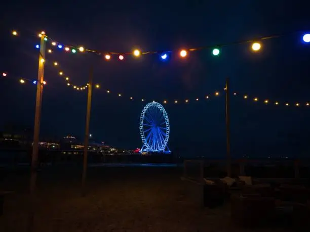 Photo of Night time panorama of lit illuminated blue sky view ferris wheel on pier of Scheveningen The Hague Netherlands Europe