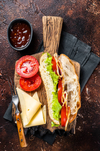 istock Smoked turkey sandwich with ham, cheese, tomato and Lettuce. Dark background. Top view 1461426302