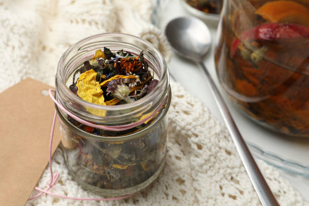 istock Glass jar with dry herbal tea and knitted fabric on table, closeup 1461426565