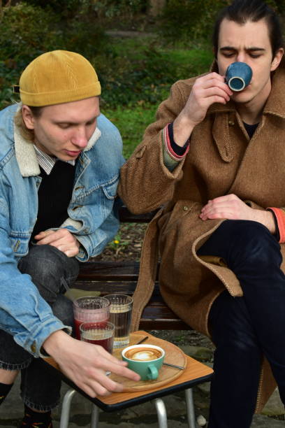 istock Two white males  drinking coffee in a public park 1461426580
