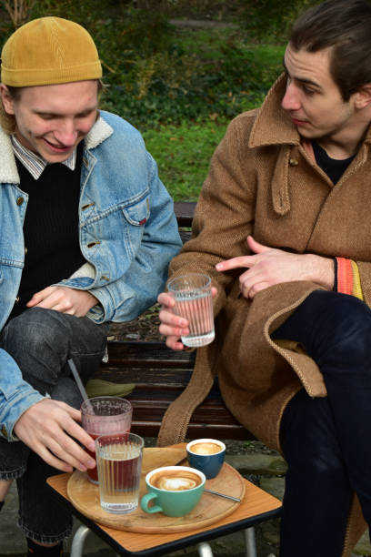 istock Two white males  drinking coffee in a public park 1461426593