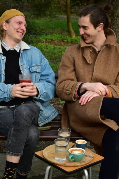 istock Two white males  drinking coffee in a public park 1461426623
