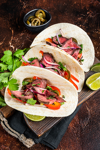 Carne Asada Tacos with grilled steak, green sauce, jalapenos and onion, Mexican food. Dark background. top view.