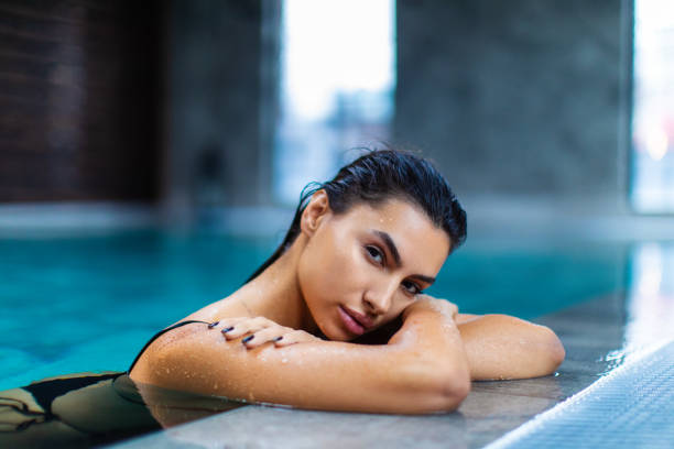 istock Beautiful young woman relaxing on indoors poolside 1461427591