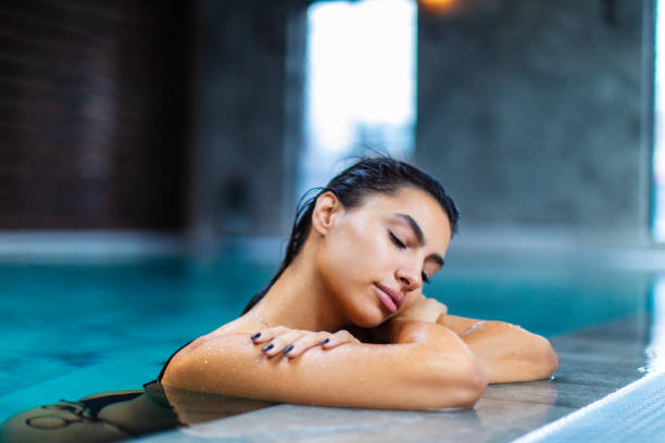 istock Beautiful young woman relaxing on indoors poolside 1461427606
