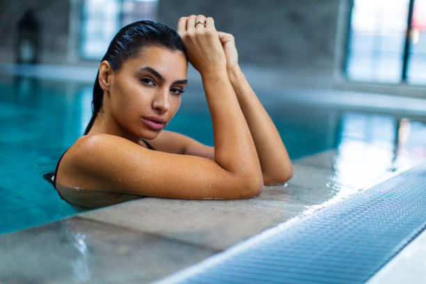 istock Beautiful young woman relaxing on indoors poolside 1461427642