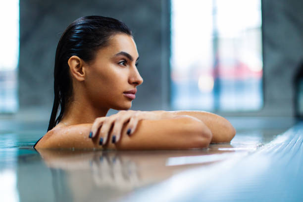 istock Beautiful young woman relaxing on indoors poolside 1461427666