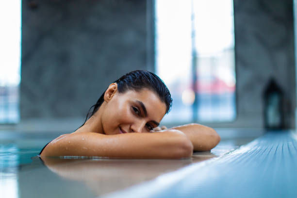 Beautiful young woman relaxing on indoors poolside