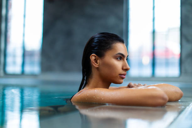 istock Beautiful young woman relaxing on indoors poolside 1461427703