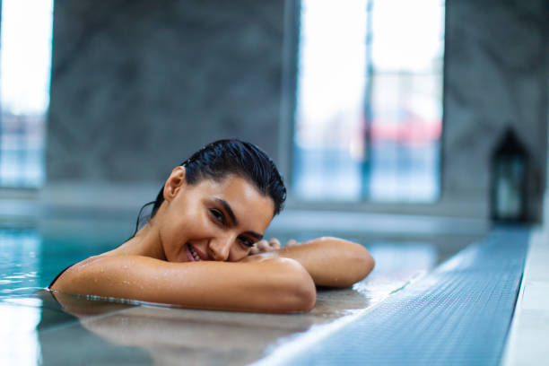 istock Beautiful young woman relaxing on indoors poolside 1461427709