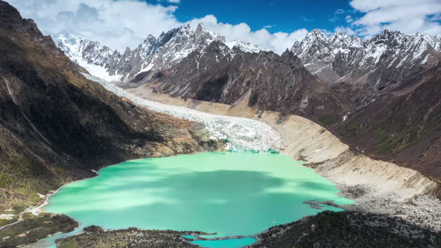A glacier poured into the green alpine lake from the top of the mountain