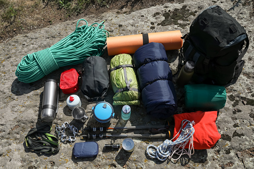 Backpack with hiking equipment on rock outdoors, above view