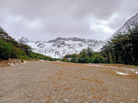 Dirt road in Andes snowy mountain range landscape. Forest track. Glaciers and Mountaineering. Landscape and extreme nature.