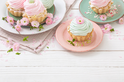 pink and green cupcakes with spring flowers on white wooden background