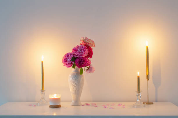 istock pink roses in vase and burning candle on background white wall 1461430754
