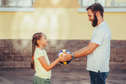 Father and daughter playing with sports ball at the schoolyard