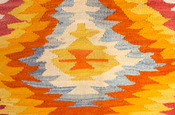 A close-up detail of a vintage wool Turkish kilim rug in orange, yellow and white.