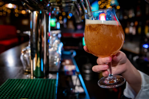 femme barman main au robinet de bière verser une bière pression dans le verre servant dans un restaurant ou un pub - Photo