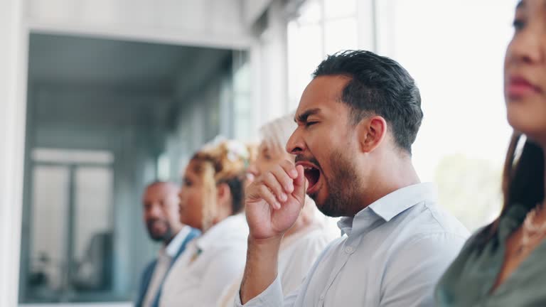 Tired, yawn and sleepless with a business man sitting in a meeting or presentation with his team for development. Yawning, exhausted and bored with a male employee suffering from insomnia at work