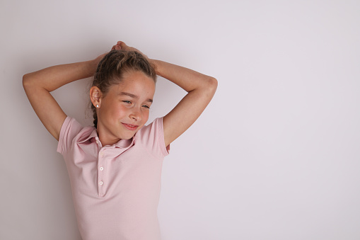 Little emotional teen girl in pink shirt 11, 12 years old on an isolated white background. Children's studio portrait. Place text, to copy space for inscription, advertising children's goods.