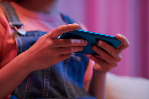 Hands of teenage girl playing game on smartphone