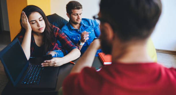 istock Sad male and female students ignoring real communication using modern gadgets in coworking space, young woman and man feeling bored during cooperating process addicted to social networks and devices 1461453882