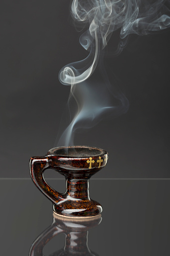 Censer with burning incense isolated on grey