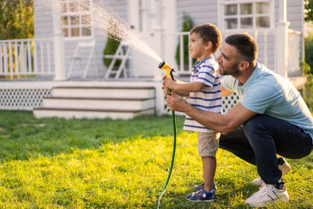 Father and son are sprinkling the grass with water