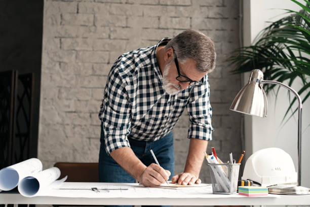 istock Mature Architect Engineer Design Working Planning Concept. Portrait of businessman working on blueprints at the office 1461457845