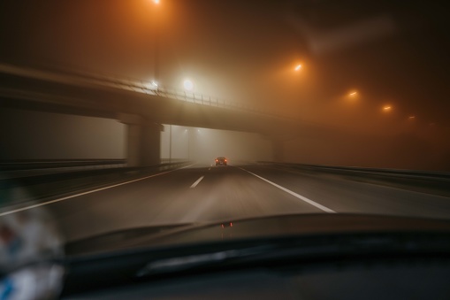 Car point of view driving on a highway at a foggy night.