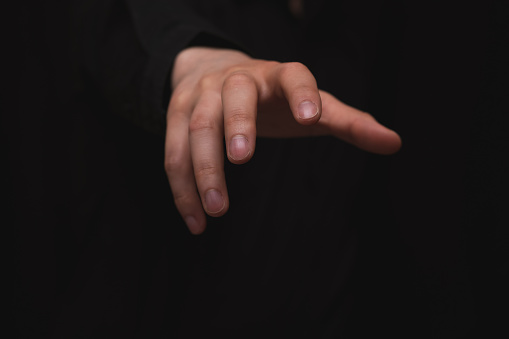 businessman stretching out his hand in a gripping pose on a black background, for corporate use.