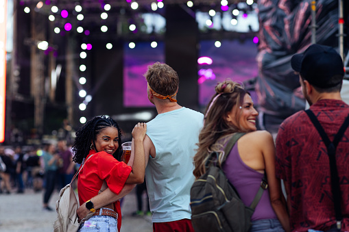 Two couples hugging, smiling and laughing together and an outdoor festival.
