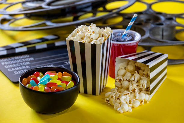Bags of Popcorn with Tickets and Movie Reels on a Yellow Background stock photo
