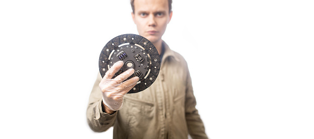 male auto mechanic with kit of new clutch disc on white background.