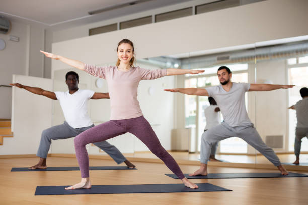 istock Girl practicing Virabhadrasana during group yoga training 1461472871